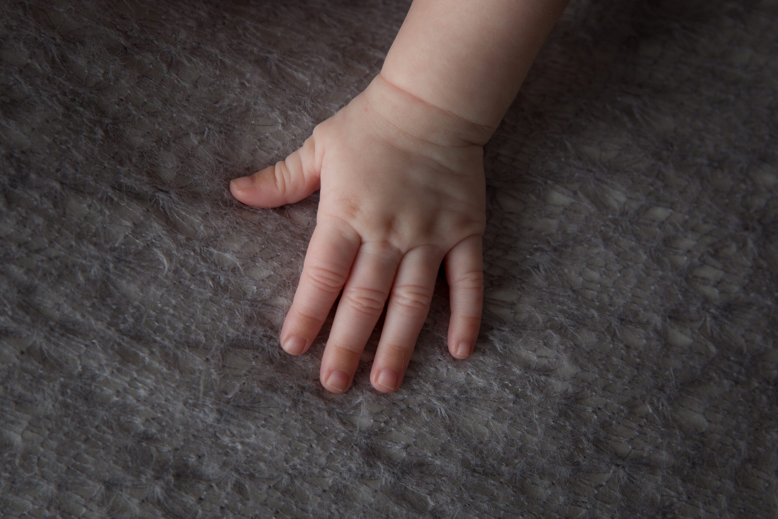 A high angle shot of the soft and chubby hand of a baby  on a fluffy cloth